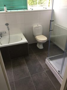 Badkamer met donkere vloertegels op de vloer en de ombouw van het bad. Inspiratie-foto bij Tegelstudio Zeeland in Vlissingen
